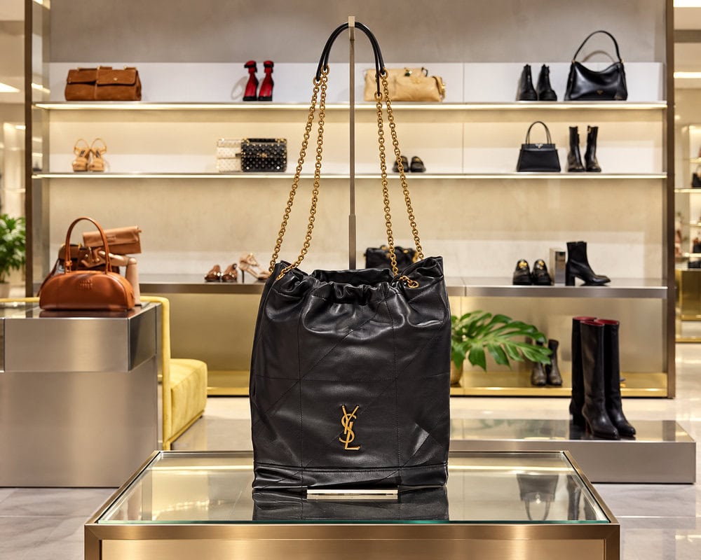 Модные коллекции брендов - чёрная кожаная сумка Saint Laurent с золотистой цепочкой на витрине бутика