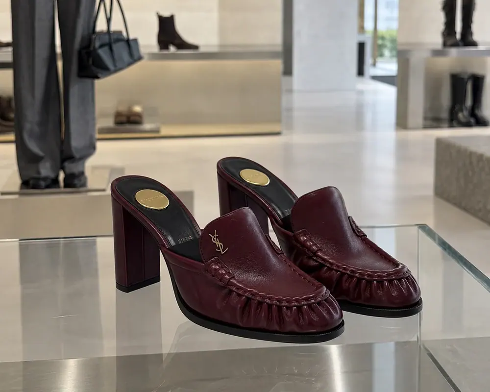 Бренд Saint Laurent - бордовые кожаные мюли на высоком каблуке с декоративной строчкой в бутике.